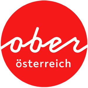 This image shows a simple logo design for "ober österreich" (Upper Austria) featuring white text on a bright red circular background. The word "ober" is written in a flowing, cursive script style, while "österreich" appears below it in a simpler font with umlauts over the 'o'.