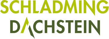 This is a logo for "Schladming Dachstein" in a modern, stylized design. The text is presented in a lime green color with a distinctive "A" that resembles a mountain peak or triangle in the word "Dachstein."